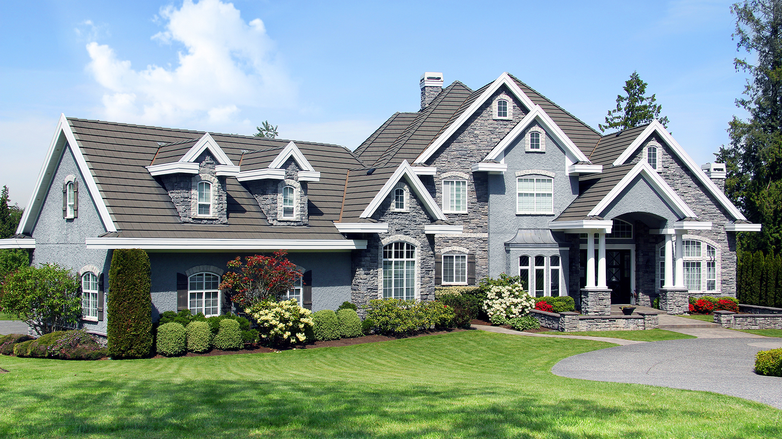 Beautiful luxury mansion with manicured front lawn. 